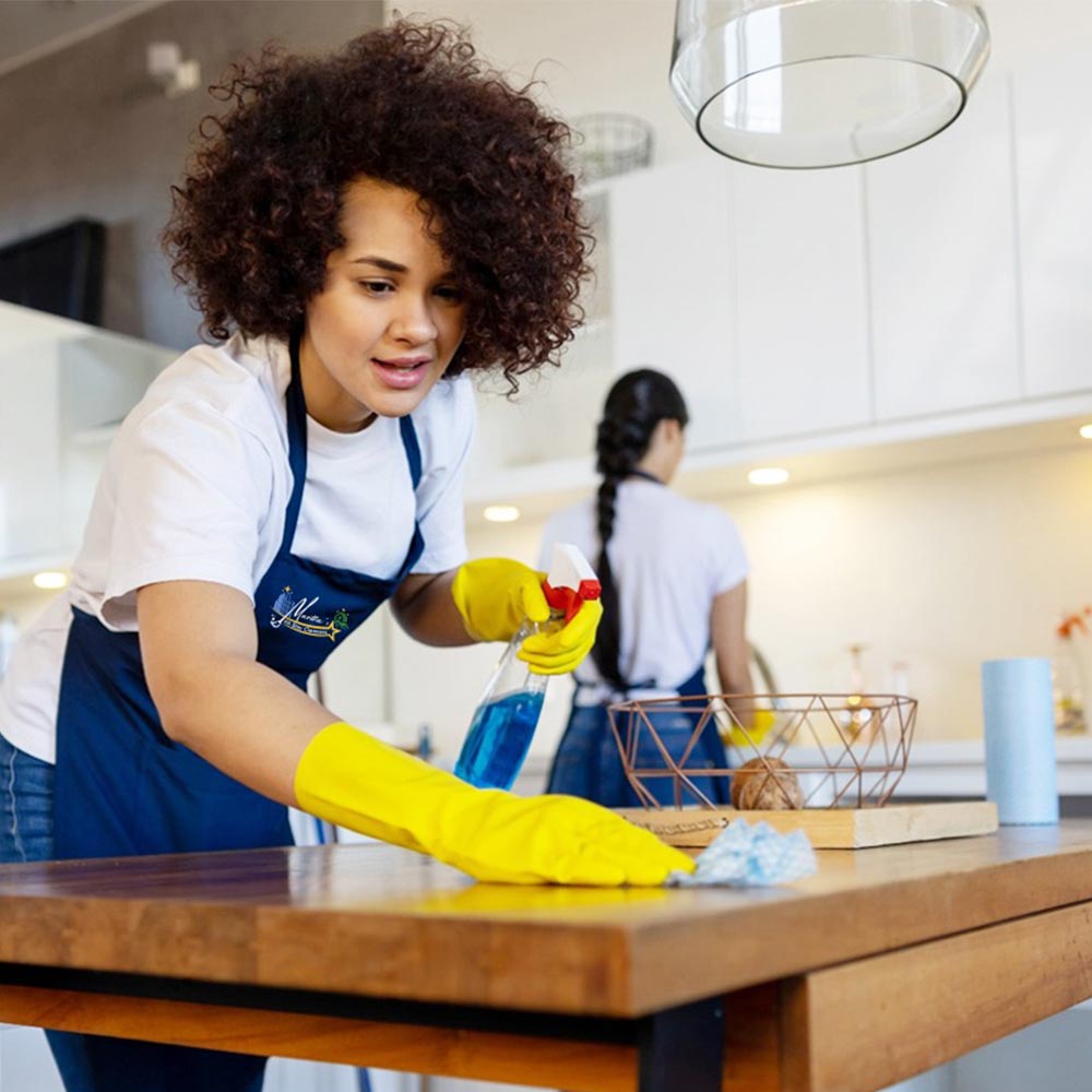 Cleaner wiping empty kitchen backsplash and counters before tenant final walkthrough
